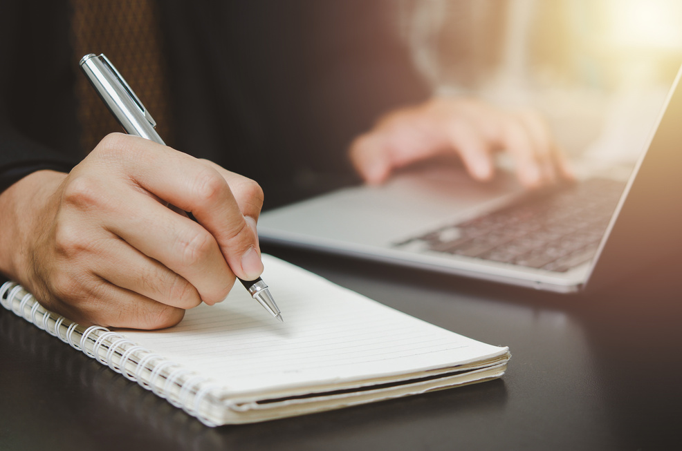 person man holding pen write plan or idea on book with compu